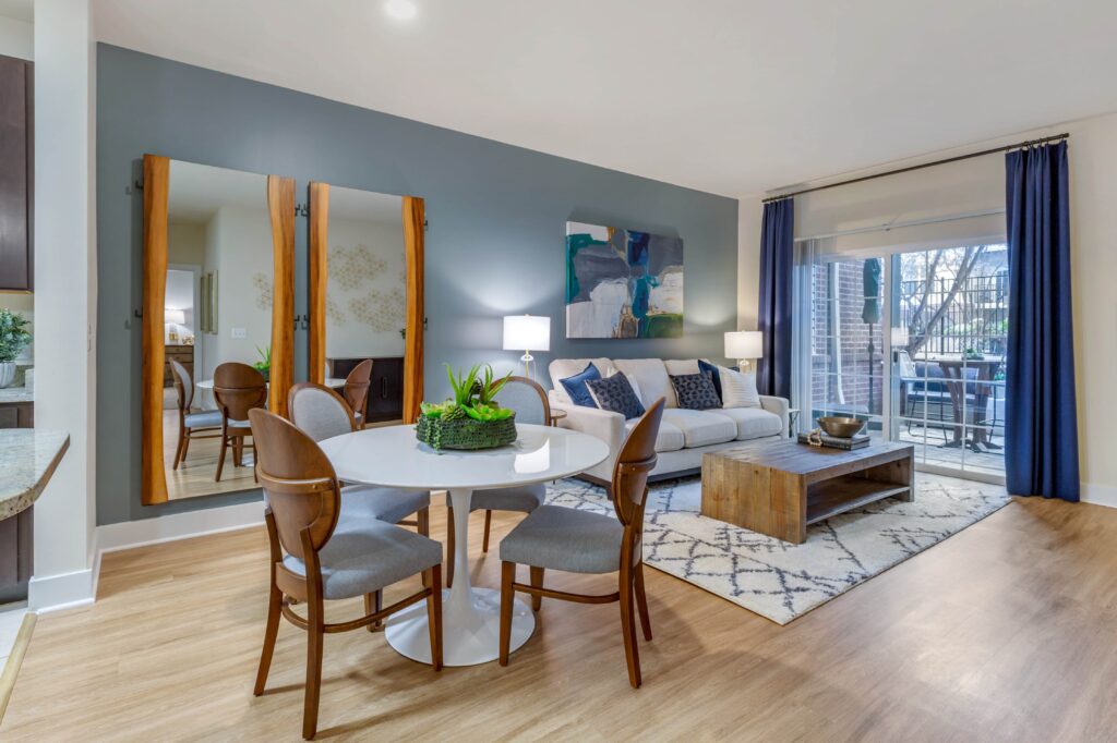 Living room with a blue accent wall and plenty of room for a dining table and couch. Extra large windows overlooking a balcony.